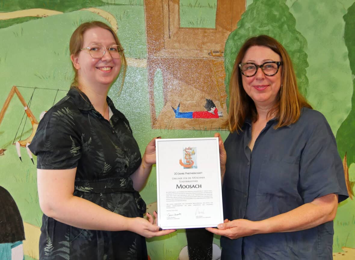 Miriam Weber von der Stadtbibliothek Moosach erhält von Caremn Deiseroth Dank und Urkunde für 20-jährige gute Zusammenarbeit.