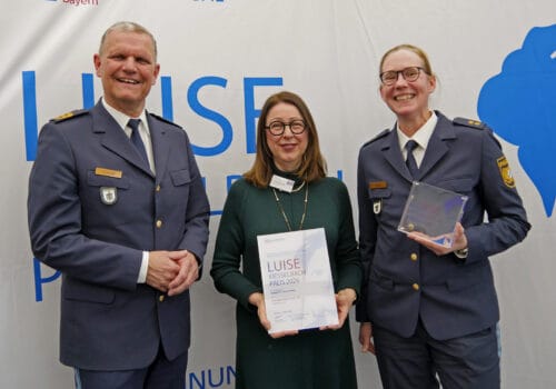 Drei Preisträger mit Urkunde vor einem Rollup der Parität.