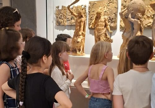 Kinder betrachten Herkulesfiguren.